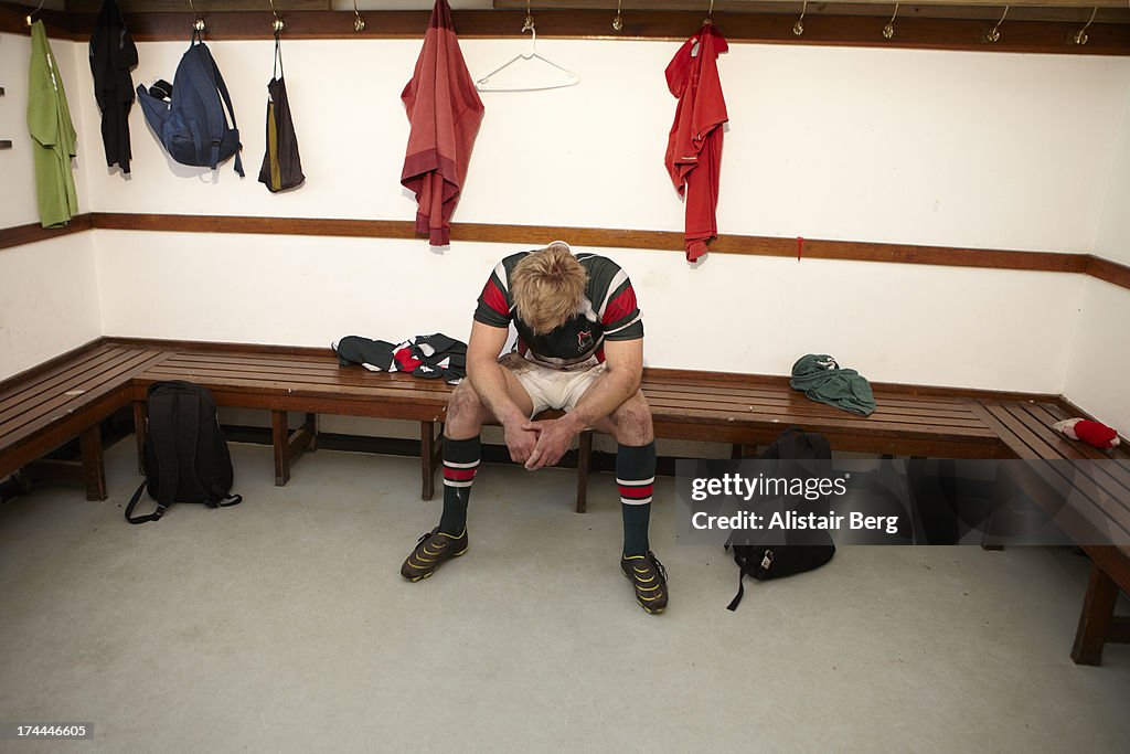 Dejected rugby player sitting in changing room