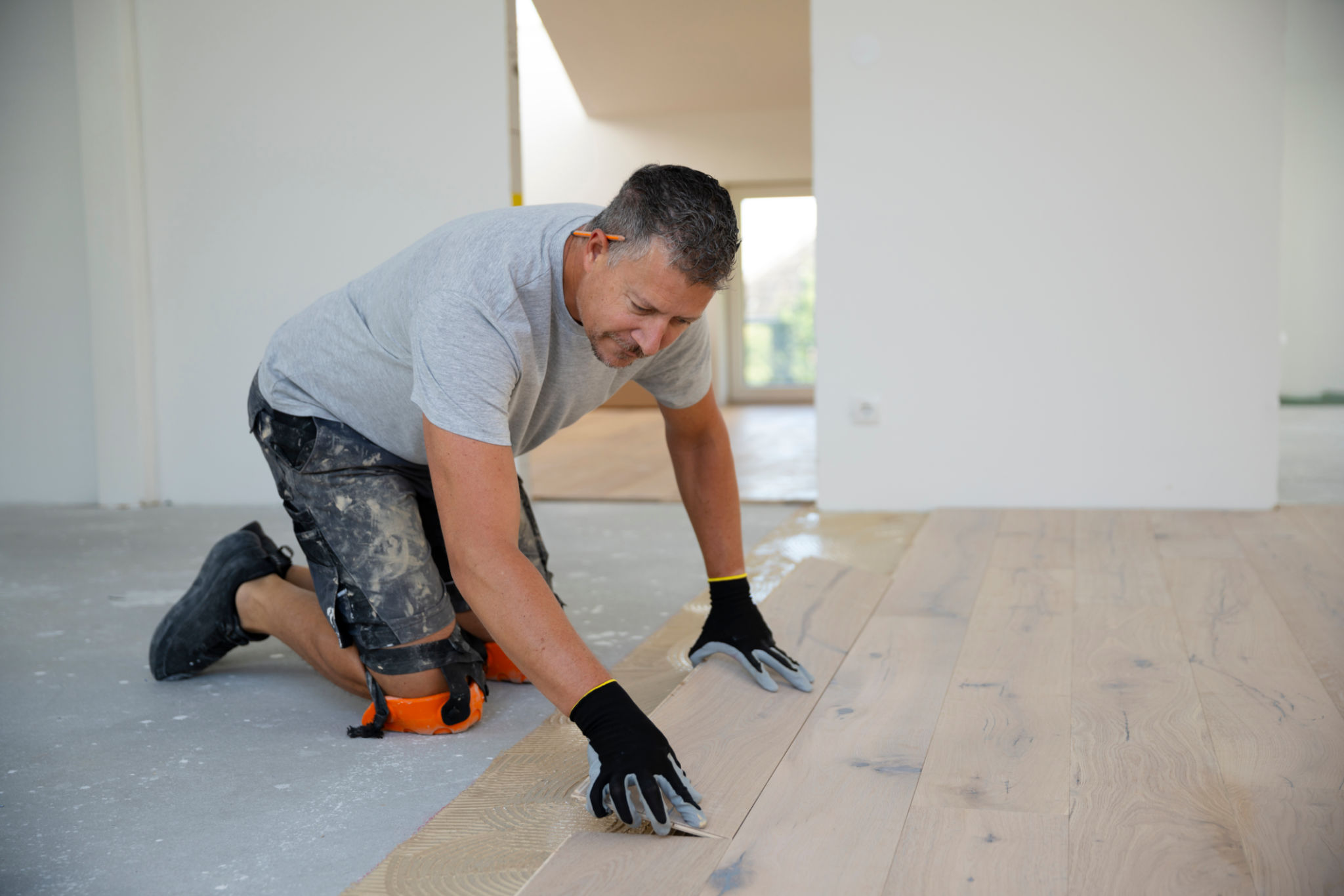 middle-aged man with gray hair glues, lays parquet floor middle-aged man with gray hair glues, lays parquet floor