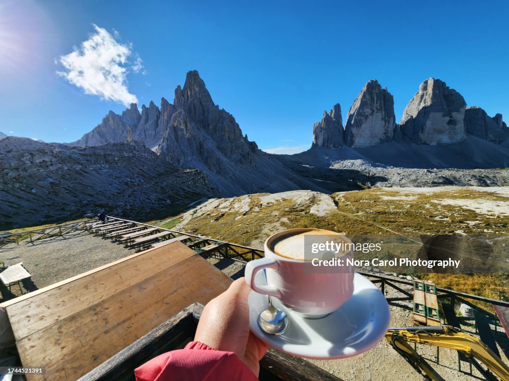 Hand Holding Cup of Cappuccino with Tre Cime di Lavaredo View