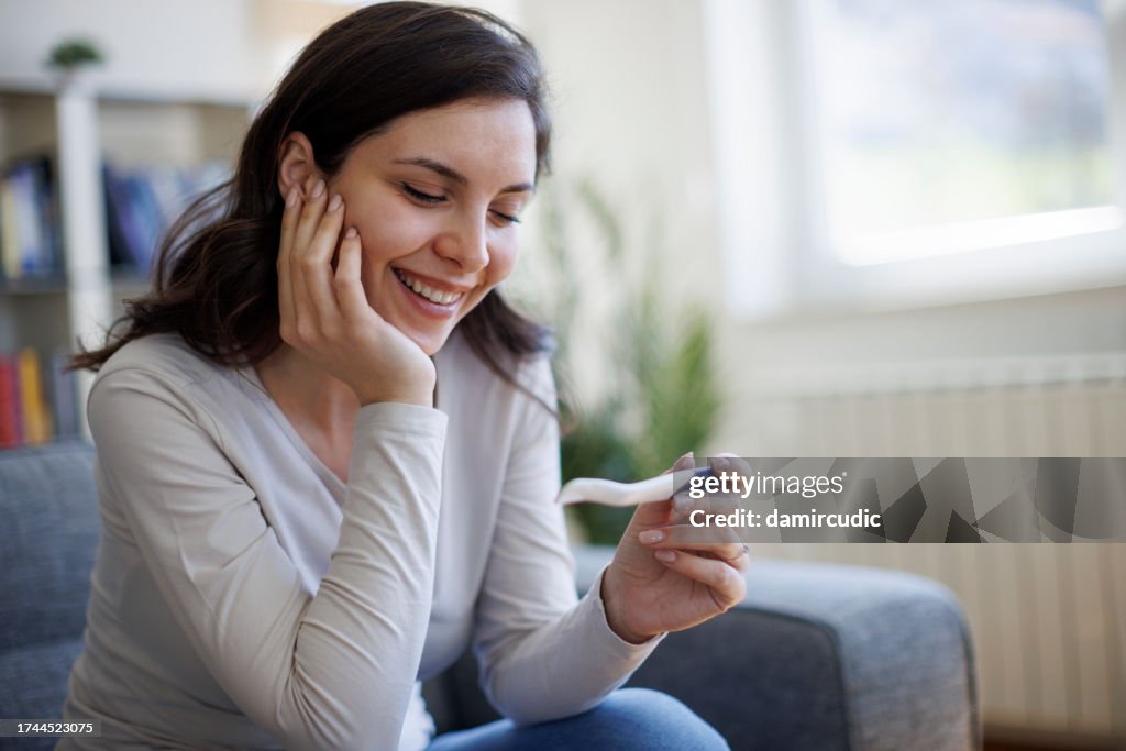 Happy young woman smiling at a pregnancy test
