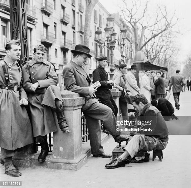 Shoeshiners at work on a street in Barcelona, Spain, April 1951. Original publication: Picture Post - 5243 - Barcelona a City in Ferment - pub. 14th...