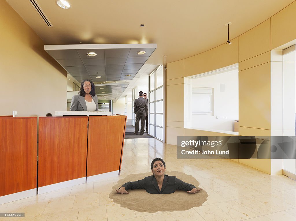 Businesswoman Sinking In Office Quicksand