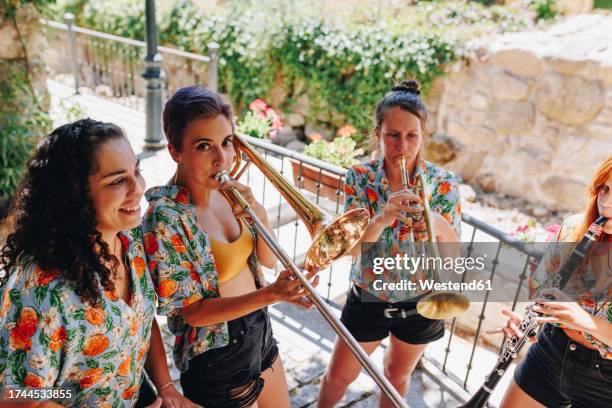 women practicing musical instruments at footpath - klarinette stock-fotos und bilder