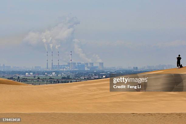 Toursit walks on the dunes near a power plant in Xiangshawan Desert, also called Sounding Sand Desert on July 17, 2013 in Ordos of Inner Mongolia...