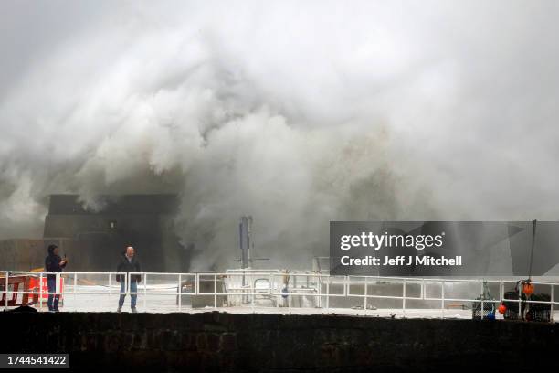 Waves crash over the harbour on October 19, 2023 in Stonehaven, Scotland. Rare Red weather warnings are in place in Scotland and amber warnings in...