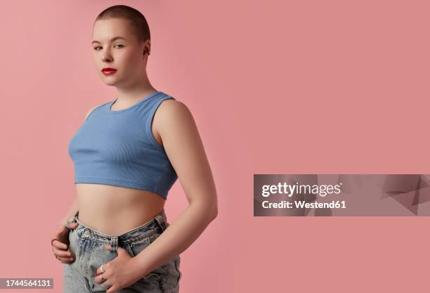 young woman posing against pink background - crop top stock pictures, royalty-free photos & images