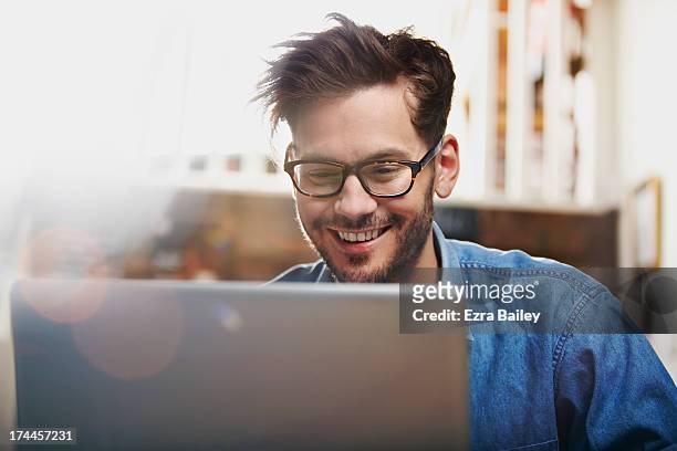 man working on a laptop in a coffee shop - computador - fotografias e filmes do acervo