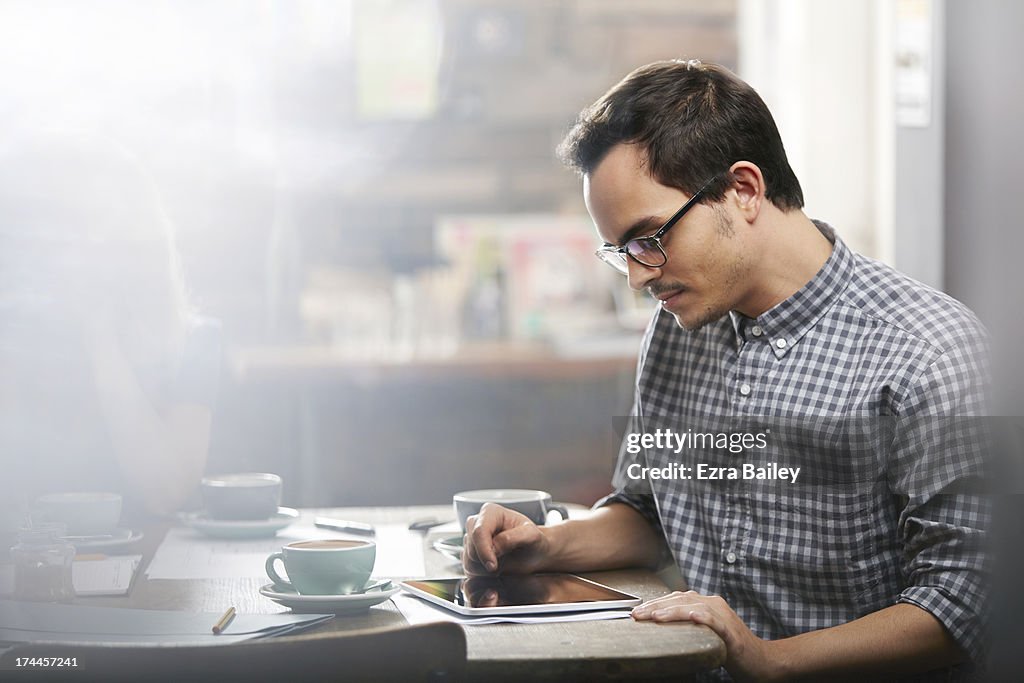 Man working on a tablet in a coffee shop.