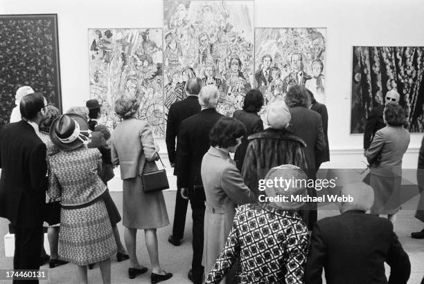 Visitors at the private view of the the Royal Academy Summer Exhibition, viewing a painting by English artist John Bratby, entitled 'The Royal...