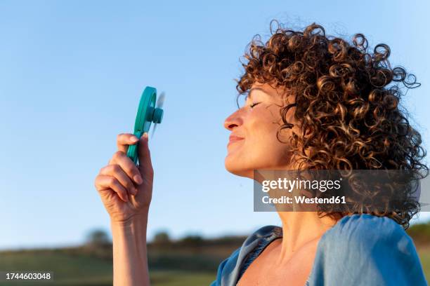 smiling woman with eyes closed holding hand fan - hand fan stock pictures, royalty-free photos & images