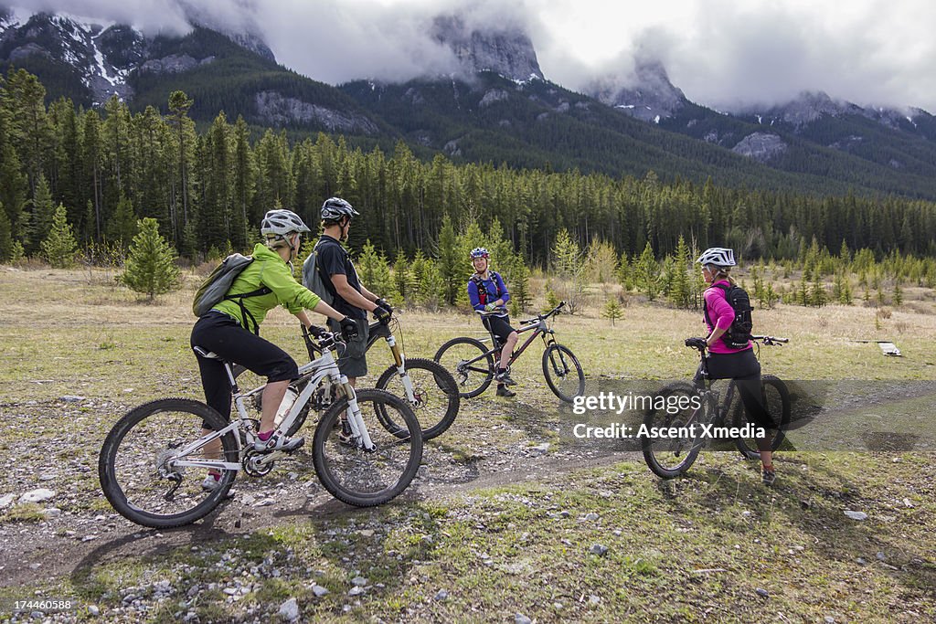 Group of bikers converse by trailside, mtns