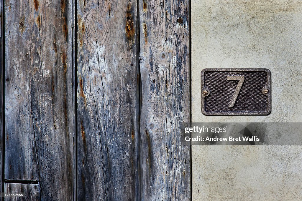 Number 7 metal sign close to an old timber doorway
