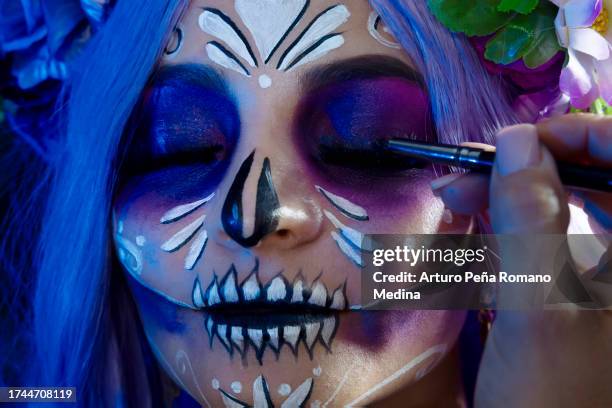 detail of the model's face being characterized as a catrina, make-up artist applying the finishing touches. - gezichtsmassage stockfoto's en -beelden