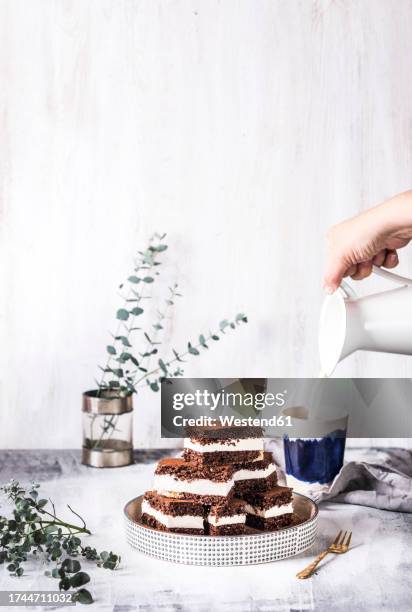 Hand Of Woman Pouring Milk In Cup With Chocolate Cake On Table, Bildbanksbilder