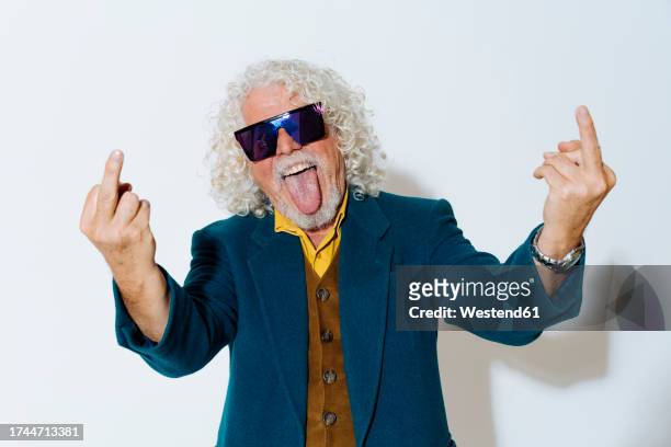 cheerful man sticking out tongue and showing obscene gesture - middle finger funny - fotografias e filmes do acervo