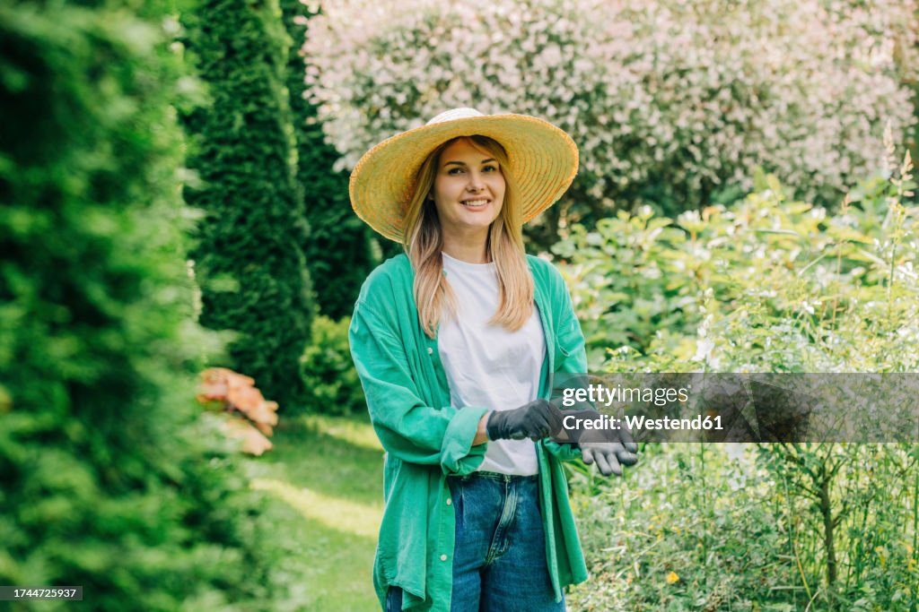 Smiling woman wearing gloves in garden