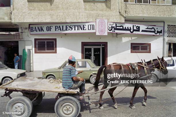 Palestinian riding a horse-kart passes by the Bank of Palestine in Gaza City on September 20, 1993. The bank of Palestine opened an office in...