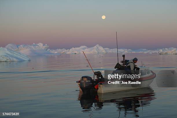 Fisherman, Inunnguaq Petersen, waits for fish to catch on the line he put out near icebergs that broke off from the Jakobshavn Glacier on July 23,...