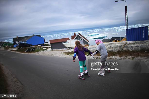 Youngsters rollerblade through the street on July 18, 2013 in Ilulissat, Greenland. As Greenlanders adapt to the changing climate and go on with...