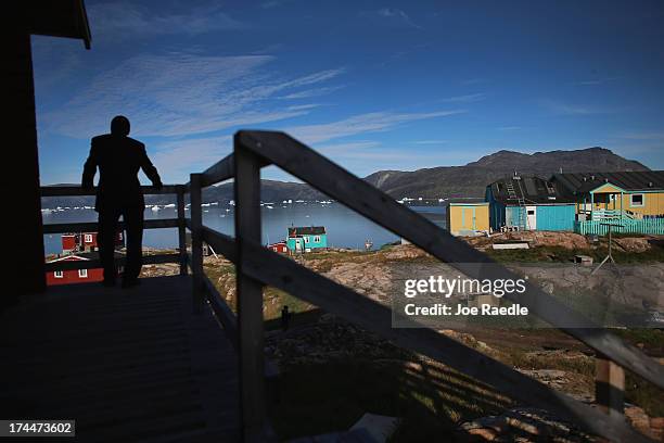 Person looks out over the village on July 20, 2013 in Qeqertaq, Greenland. As Greenlanders adapt to the changing climate and go on with their lives,...