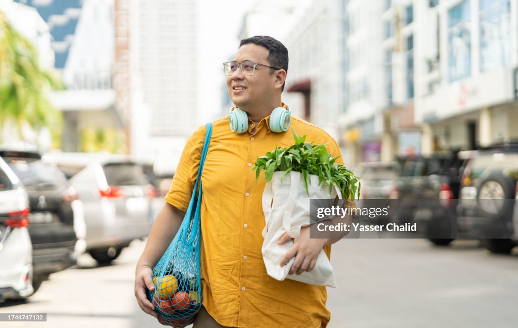 Asian man walking on street with groceries on hands
