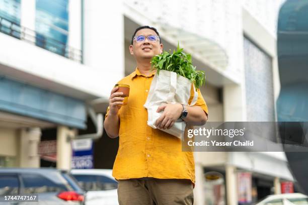 asian man walking with groceries on hand - indonesia street stock pictures, royalty-free photos & images