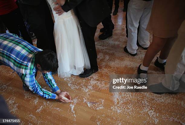 Youngster gathers up rice that was being thrown onto newly weds, Adam Olsen and his wife Ottilie Olsen on July 20, 2013 in Qeqertaq, Greenland. As...