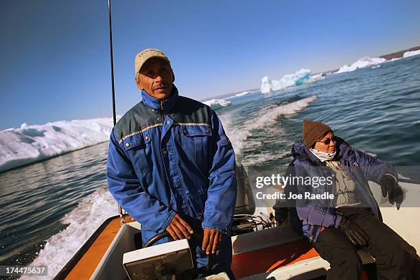 Kaalinnquaq Olsuig and his wife, Karoline Olsuig, ride in a boat past icebergs that broke off from the Jakobshavn Glacier as he heads to perform...