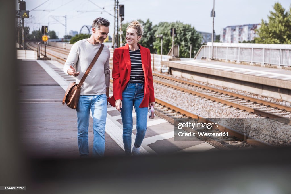 Smiling couple walking together at railroad station