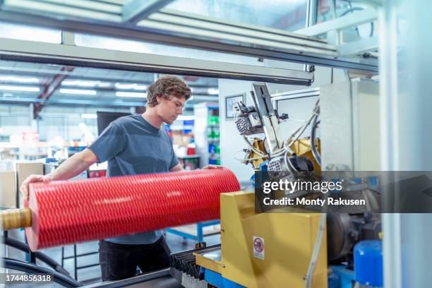 worker loading roll of tape into cutting machine in factory - preston england stock pictures, royalty-free photos & images