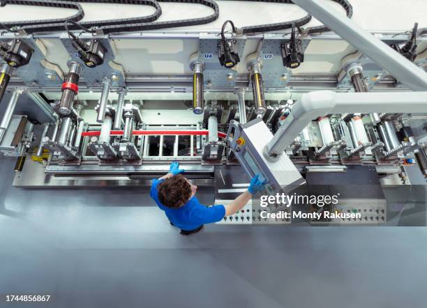 factory worker at controls of adhesive tape manufacturing machine in factory - preston england stock pictures, royalty-free photos & images