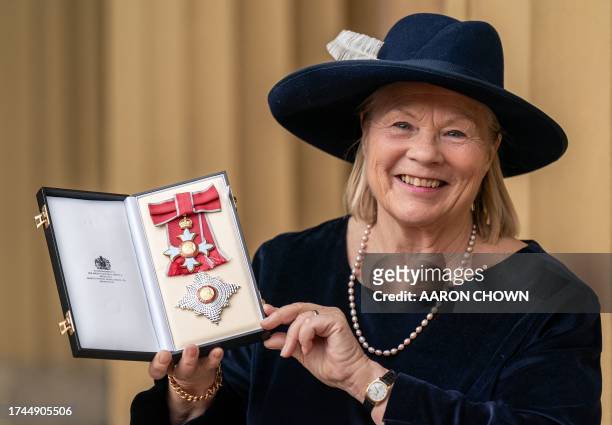 Ann Limb poses with their medal and insignia after being appointed a Dame Commander of the Order of the British Empire following an investiture...