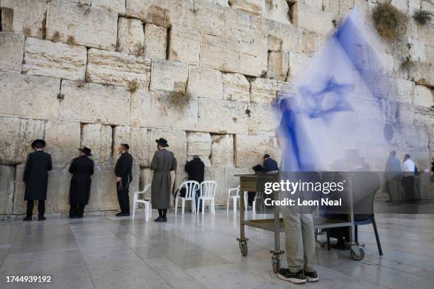 Man holds the flag of Israel as he joins others to pray at the Western Wall on October 19 in Jerusalem, Israel. As Israel prepares to invade the Gaza...