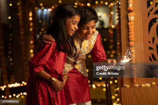 happy siblings playing with sparklers at home during diwali - indian traditional clothing stock pictures, royalty-free photos & images