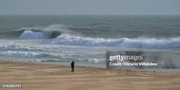 Lone beachgoer watches large waves breaking on Carcavelos Beach at the end of the afternoon after the passage of depression Aline on October 19 in...