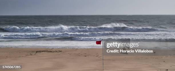 Red flag banning bathing flutters as large waves break on the deserted Carcavelos Beach at the end of the afternoon after the passage of depression...