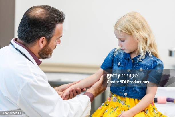 male orthopedist checks girl's arm post-surgery - elbow stock pictures, royalty-free photos & images