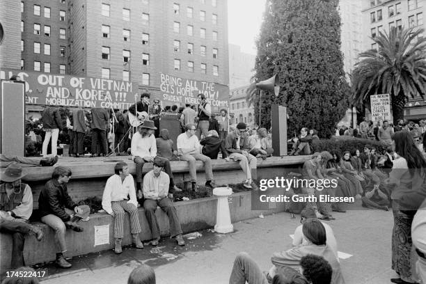 Anti-Vietnam War protesters sit in a park on Powell Street as musicians perform on stage in anticipation of the arrival of President Nixon at the St....