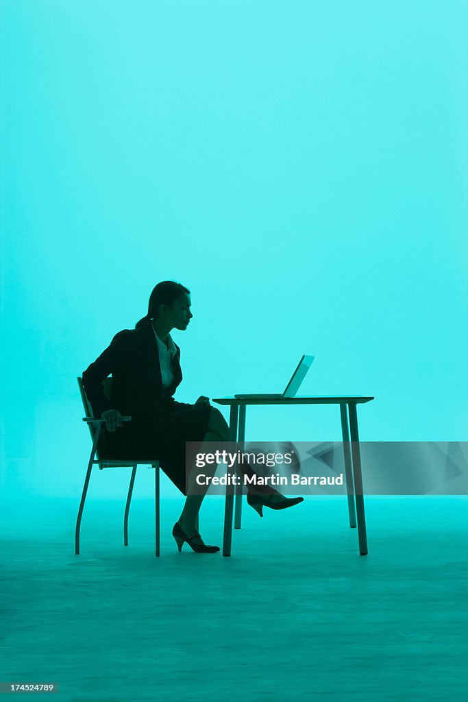 Businesswoman by a table with laptop on it