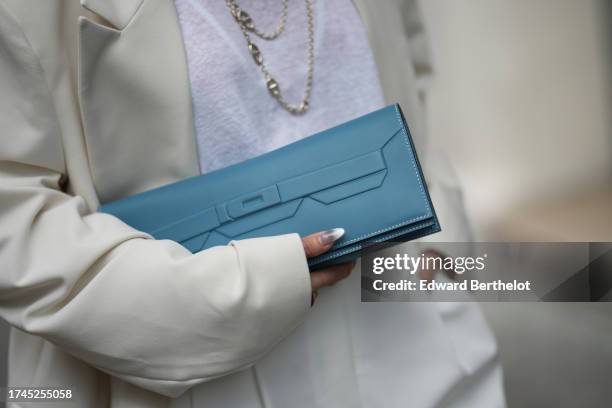 Heart Evangelista wears a white t-shirt, a white oversized blazer jacket, white wide leg suit pants, a blue Hermes clutch / rectangular leather bag,...