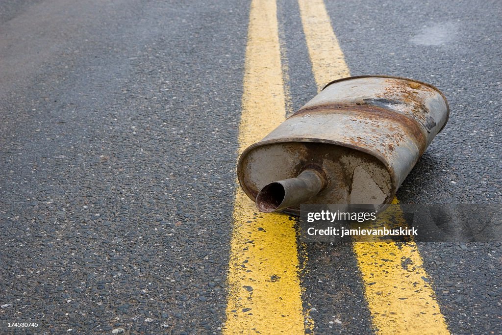 Old rusted muffler laying in the center of the road