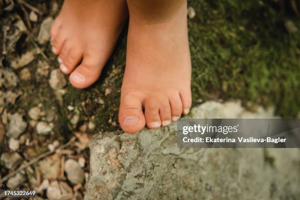 children's bare feet on the ground covered with green grass and stones - barefoot child stock pictures, royalty-free photos & images