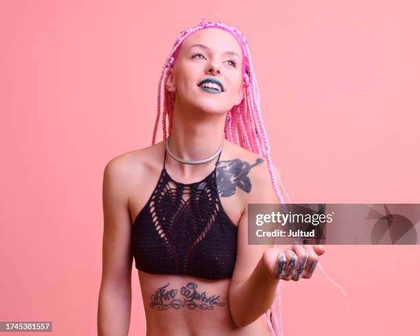 tattooed girl with pink dreadlocks on pink background smiles and makes expressive gestures - tattoo shoulder stock pictures, royalty-free photos & images