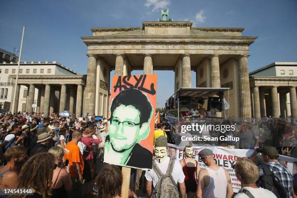 Participant holds up a picture of former NSA employee Edward Snowden with the word "asylum" written above it at a protest gathering in front of the...