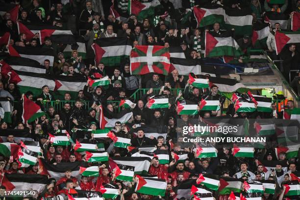 Supporters hold Palestinian flags as they cheer prior to the start of the UEFA Champions League group E football match between Celtic and Atletico...