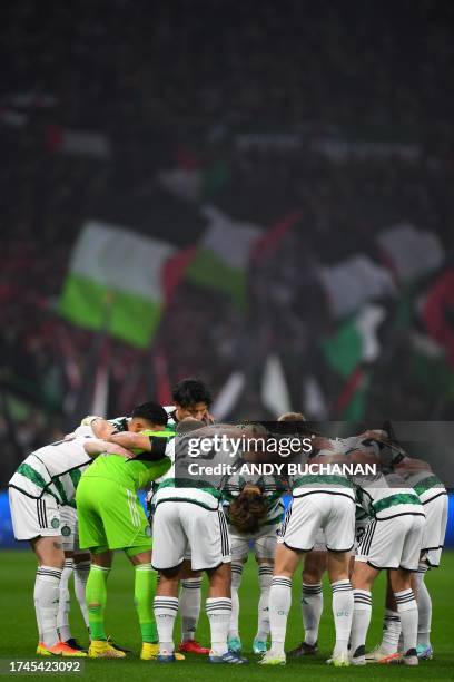 Celtic's players gather to speak as Palestinian flags are waved by supporters in the background during the UEFA Champions League group E football...