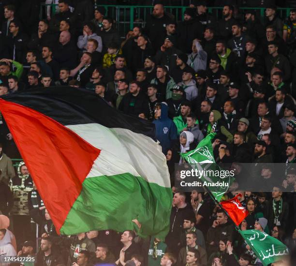 Supporters hold Palestinian flags as they cheer prior to the start of the UEFA Champions League group E football match between Celtic and Atletico...
