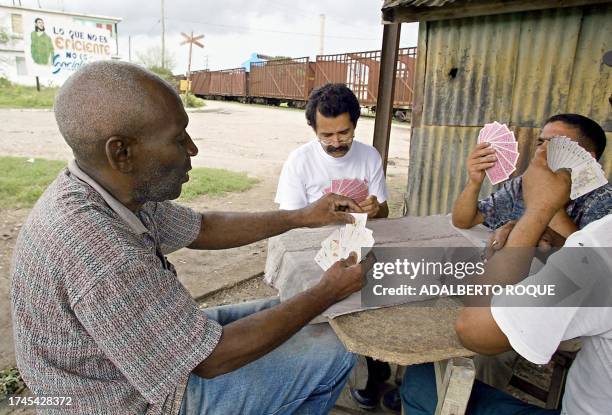 Group of men from the sugar industry play cards during their leisure time, in San Luis province of Santiago, Cuba, 09 June 2002. AFP PHOTO/Adalberto...