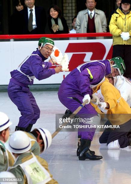 Businessmen in training gear play tug-of-war on an ice rink as a colleague shouts encouragement during the 13th annual Hibiya tug-of-war tournament...