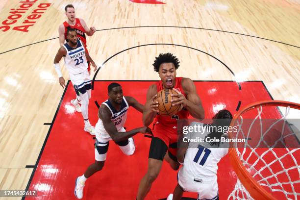 Scottie Barnes of the Toronto Raptors jumps to the net for a dunk against Naz Reid of the Minnesota Timberwolves during the first half of their NBA...